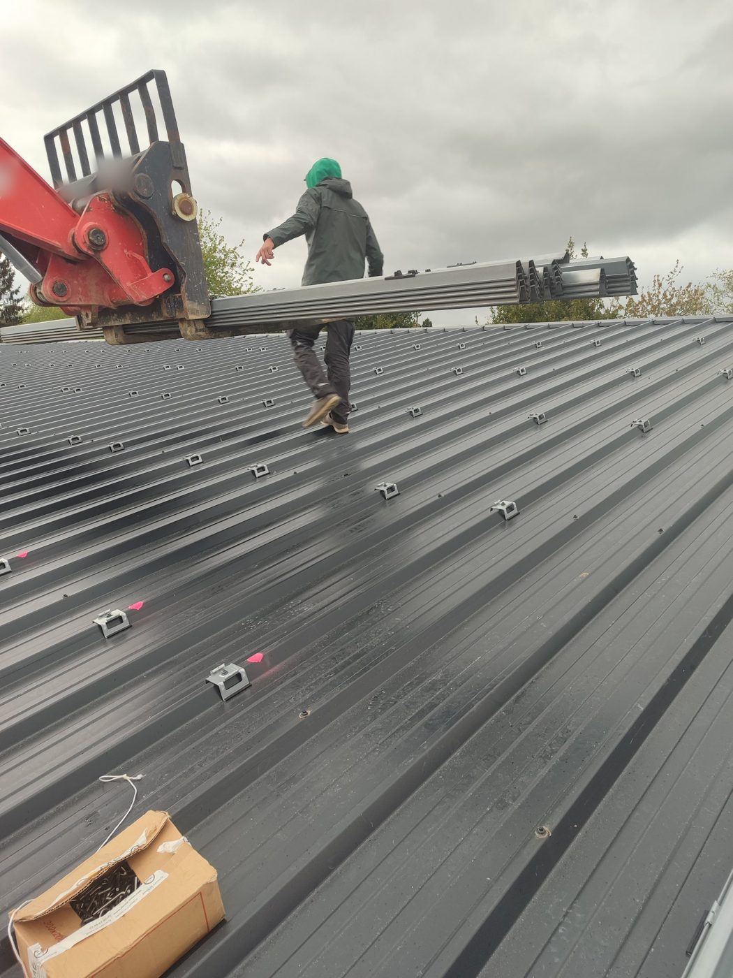 Technicien sur une toiture bac acier pendant la pose des rails de fixation
